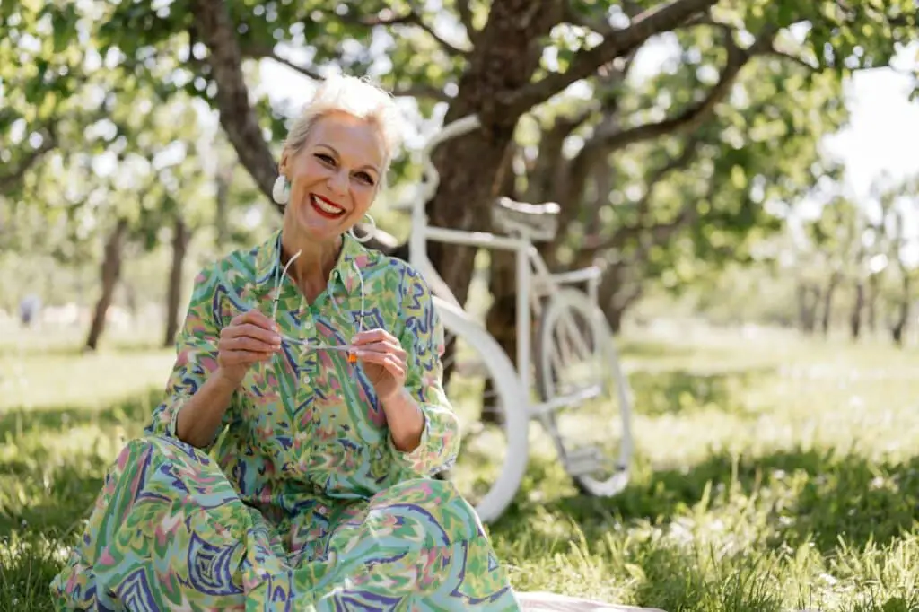 Senior woman in a trendy printed dress enjoying a sunny day in a park.